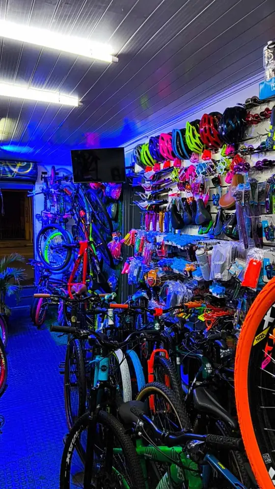Interior da loja iluminado, com bicicletas e peças