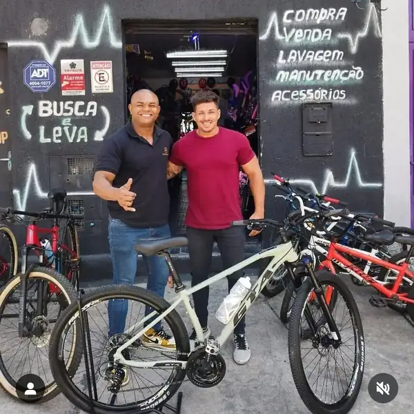 Cliente recebendo bicicleta branca na porta da loja
