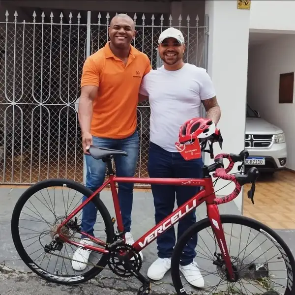 Cliente recebendo bicicleta speed vermelha na loja